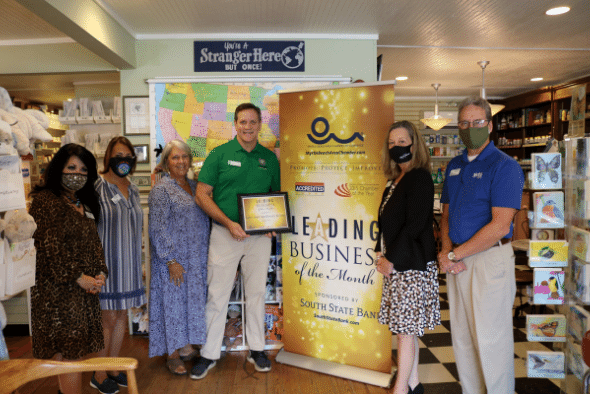 group of people in front of banner reading leading business of the month
