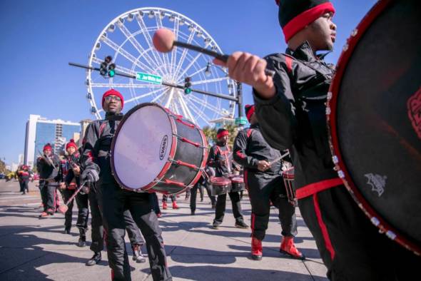 drummers walk in parade with skywheel behind them