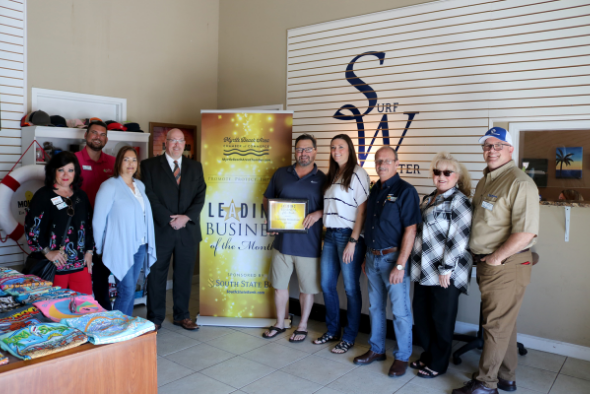 group of people in front of banner reading leading business of the month