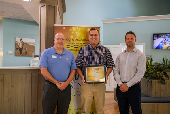 lakewood campground representatives stand with james steadman of south state bank holding an award