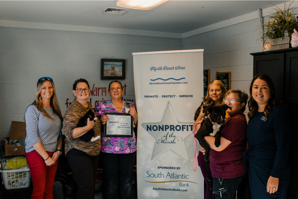 North Myrtle Beach humane society volunteers smile for photo while holding a cat and dog