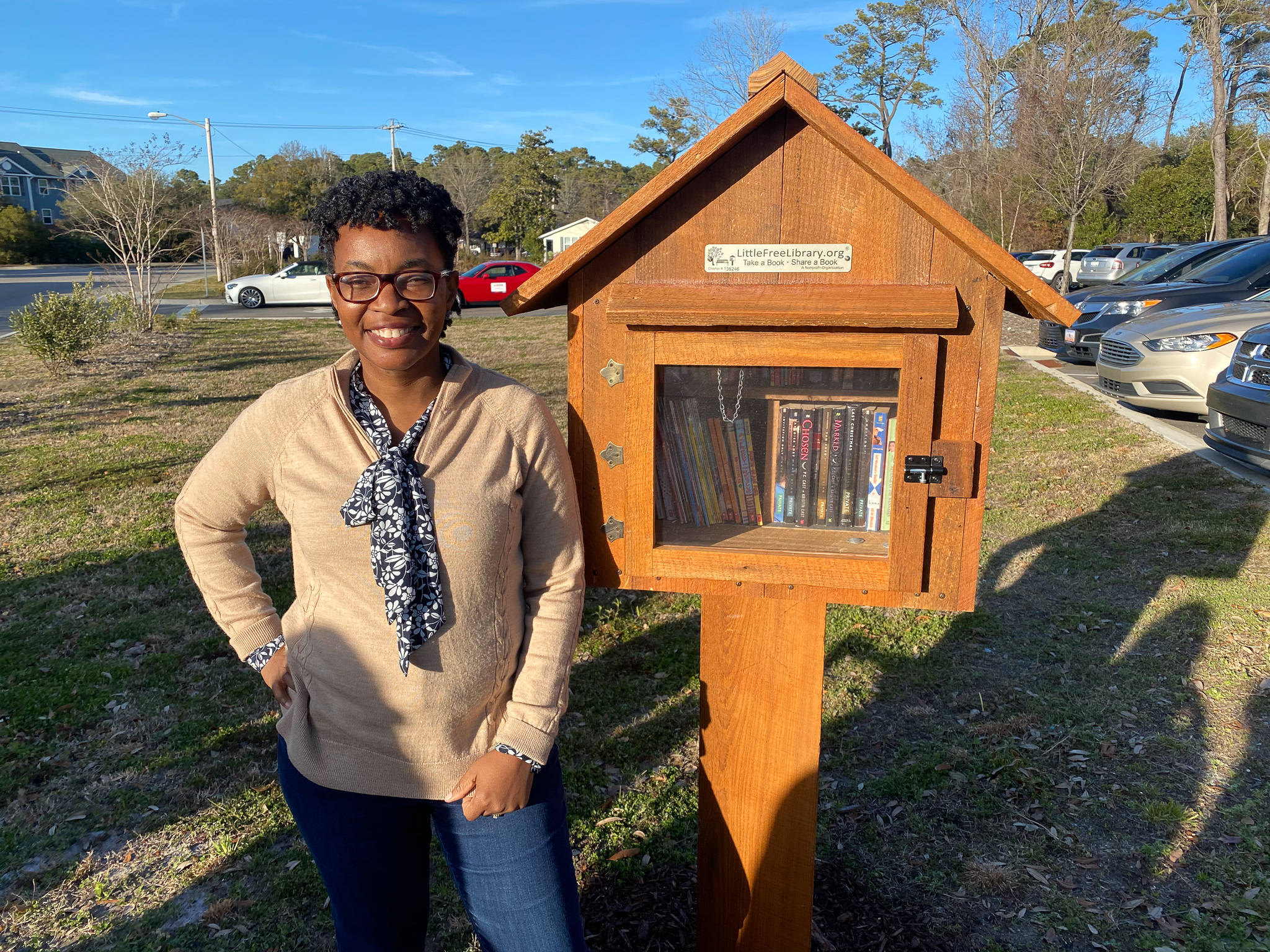 Tracy Bailey stands in front of wooden little free library