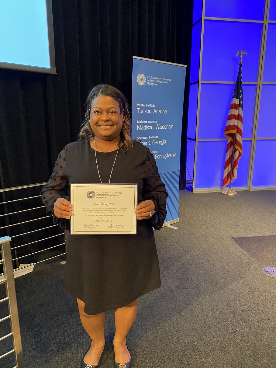 Kema Parsley smiles with an IOM graduation certificate 