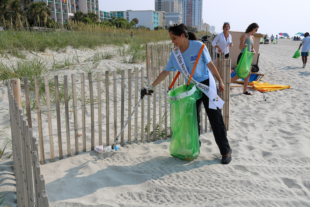 Miss North Myrtle Beach Brooke Vu cleans up trash in the sand during a beach cleanup.